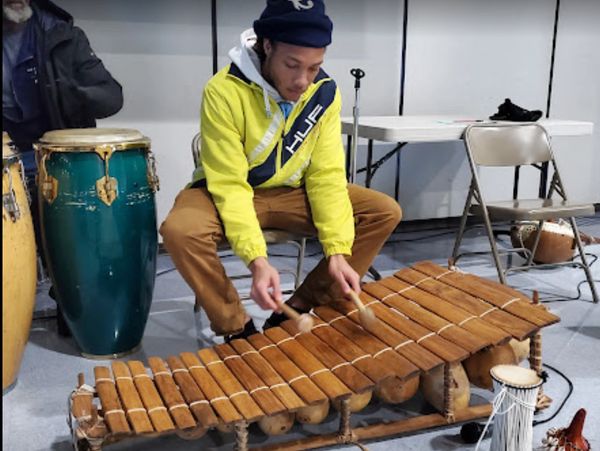 Man playing a wooden xylophone with mallets indoors.