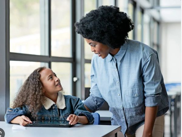 Teacher encouraging a student during class with a tablet.