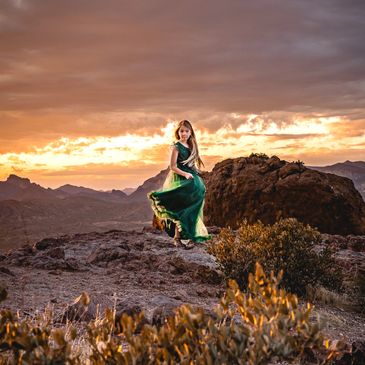 Child photography with girl on a mountain at sunset in a green flowing formal dress