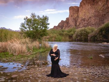 Maternity photo at AZ Salt River Water Users by mountain with a woman in a black maternity gown.