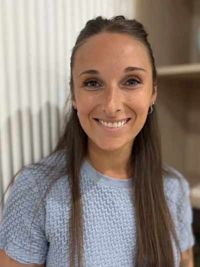 Jeune femme souriante avec un haut bleu à manches courtes.