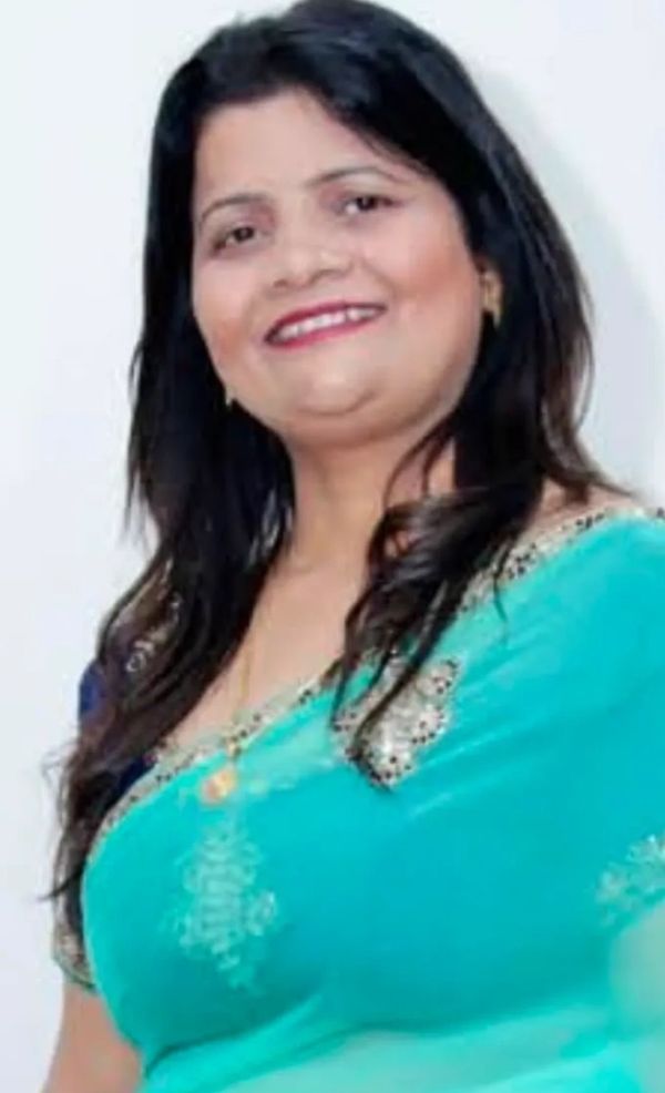 Smiling woman in a turquoise saree with gold accents.