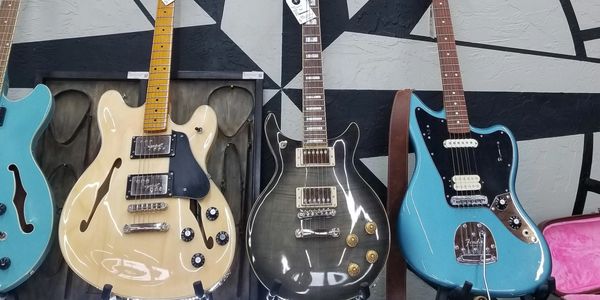 Three electric guitars displayed side by side.