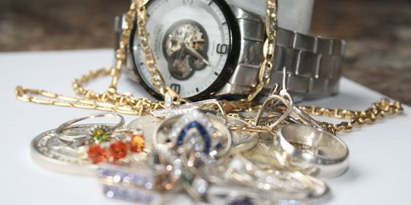 Close-up of jewelry and wristwatch on white surface.