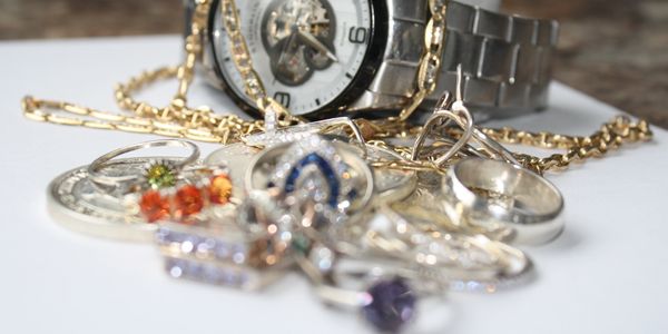 Close-up of jewelry and wristwatch on white surface.