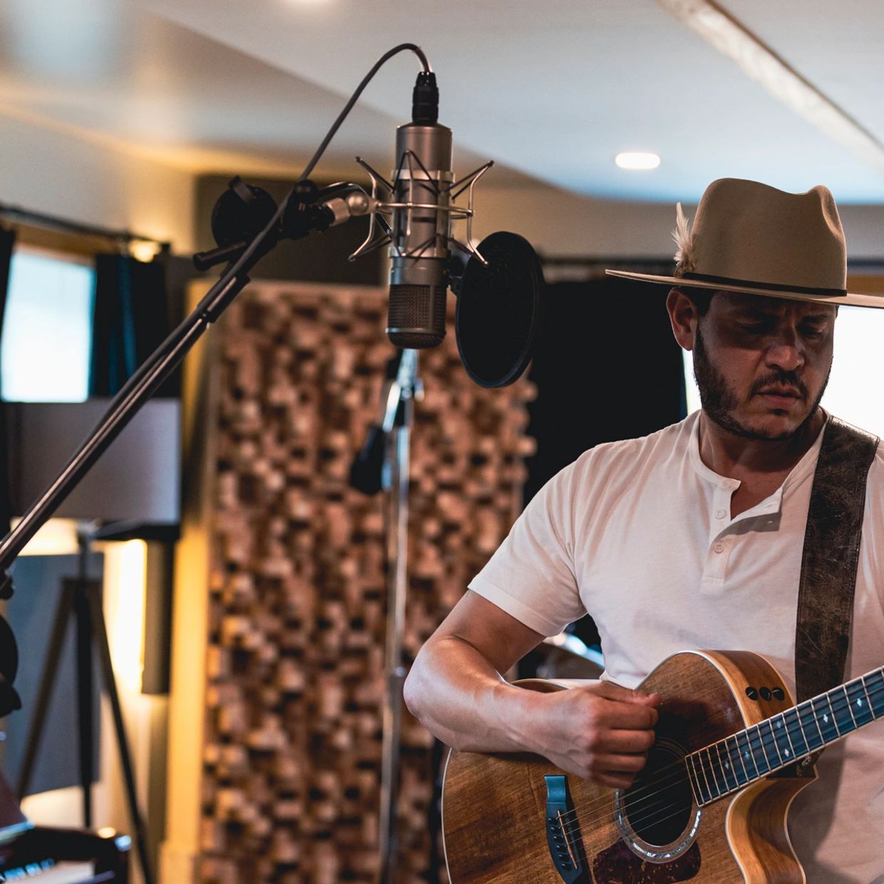 Man playing guitar and singing in a recording studio.