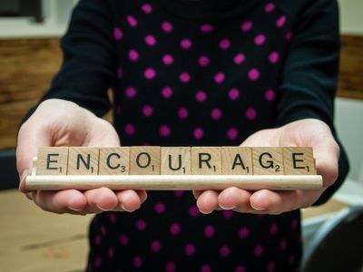 Person holding sign saying "encourage" 