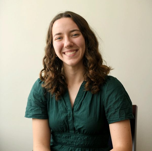 Smiling young woman with curly hair in green dress.