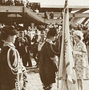 Black and white photo of a formal ceremony with a woman and uniformed guards.