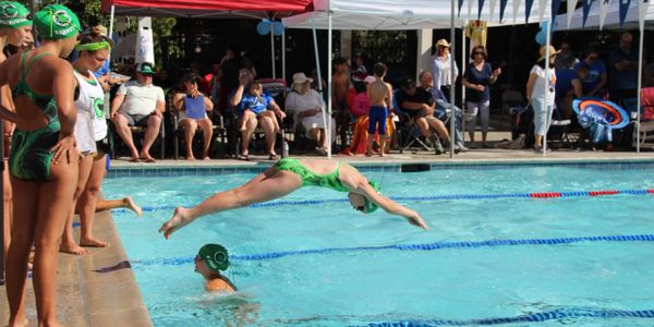 Young swimmer diving into pool during a swim meet.