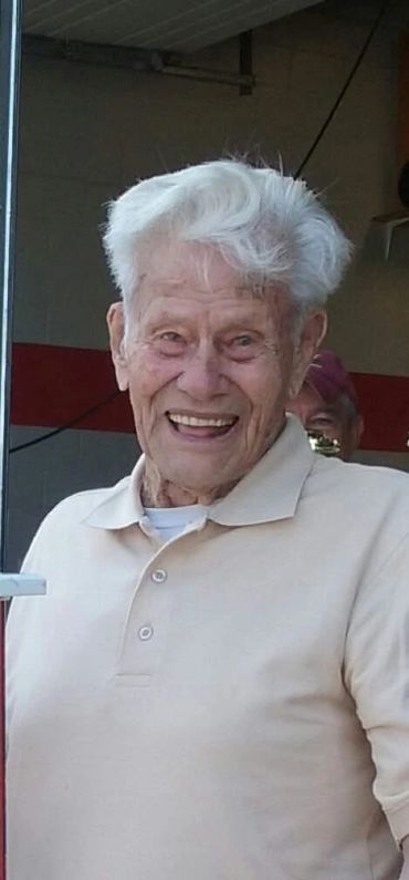 Elderly man with white hair smiling warmly indoors.