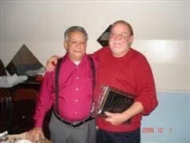 Two men posing together, one holding a musical instrument.
