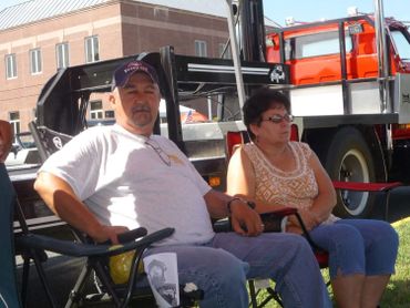 A man and woman sitting outdoors in lawn chairs on a sunny day.