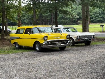 Two classic cars parked on a gravel area.