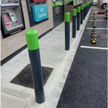 Green-topped bollards line a sidewalk outside an off-licence store.