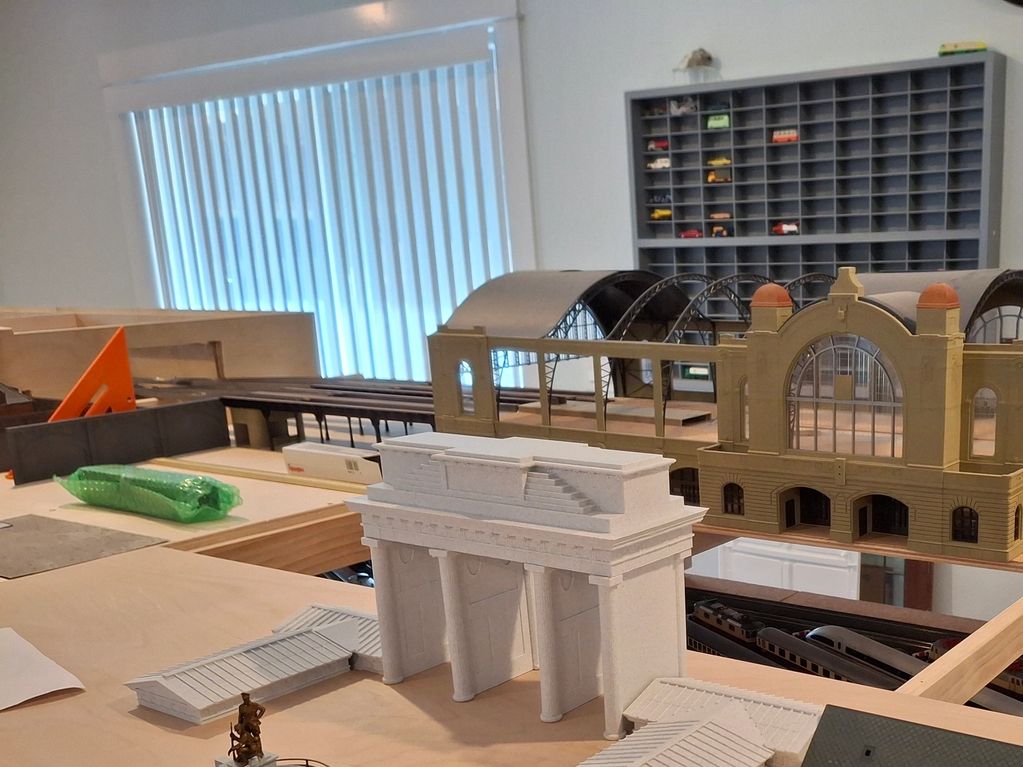 Model train station under construction with detailed building parts.