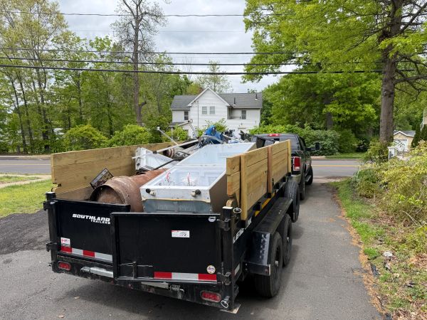 A black trailer loaded with various metal items and equipment.