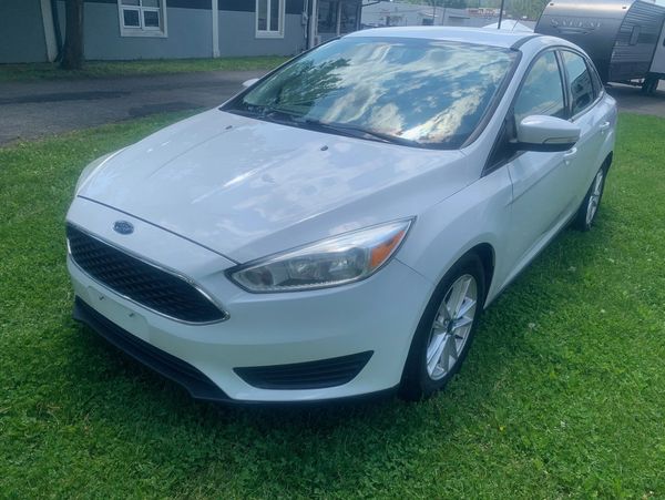 White Ford sedan parked on green grass near houses.