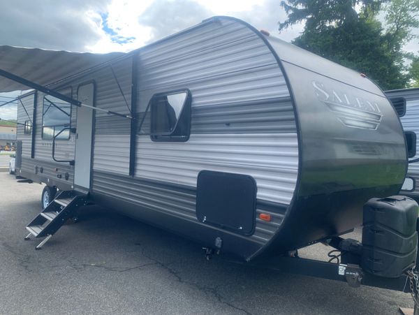 Silver and black Salem travel trailer parked with steps extended.