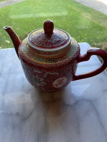Decorative red and gold teapot with intricate floral and geometric patterns.