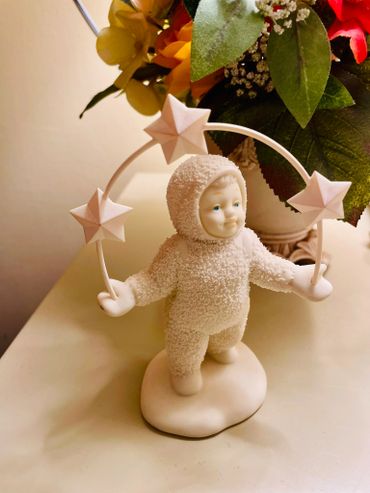 A white figurine of a child holding a star-decorated hoop.