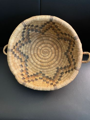 Handwoven basket with geometric patterns and side handles.
