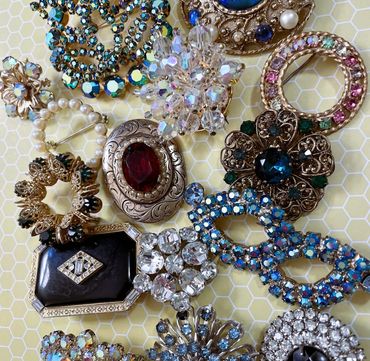 A collection of vintage brooches with colorful gemstones on a honeycomb-patterned background.