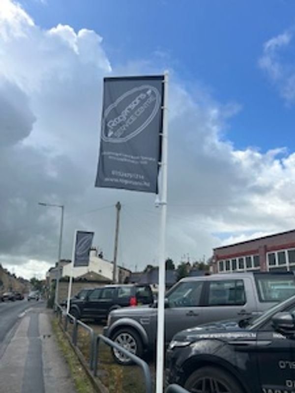 Flags displaying 'Cooperatives West Cork' along a street with parked cars.