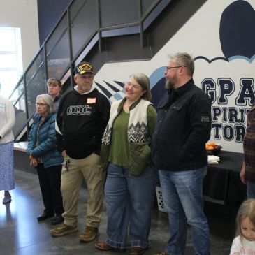 Group of people standing indoors near a staircase.
