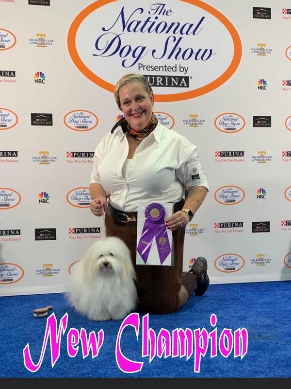 Woman with fluffy dog and champion ribbon at National Dog Show.