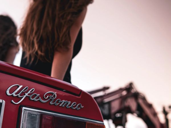 Close-up of a red Alfa Romeo car with a person in the background.