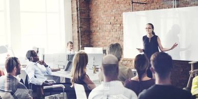 The presenter is surrounded by a satisfied audience in front of the whiteboard. Hotel opening