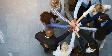 Ten people are standing in a circle with stretched arms, touching each other's hands. Task force 