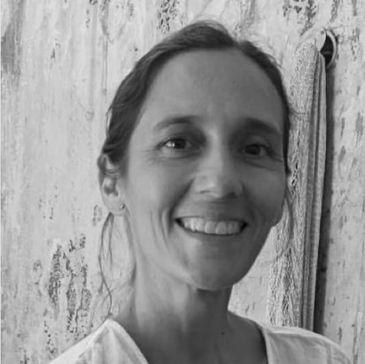 Black and white portrait of a smiling woman with a textured wall background.