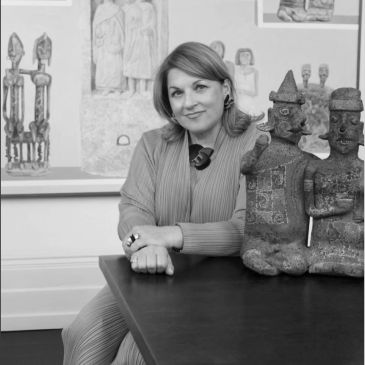 Woman sitting next to two ancient sculptures in a gallery.