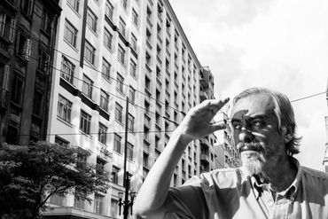 Man shielding his eyes from the sun on a city street.