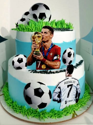 Two-tiered cake decorated with soccer balls and Cristiano Ronaldo images.