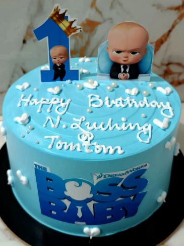 Blue Boss Baby-themed birthday cake with figurines and decorations.