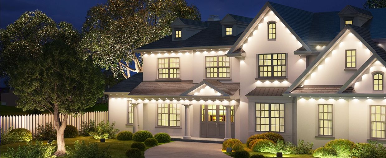 A large, well-lit house with a beautiful garden at night.