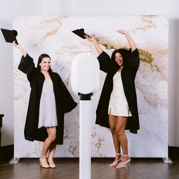 Two graduates celebrating with caps and gowns.