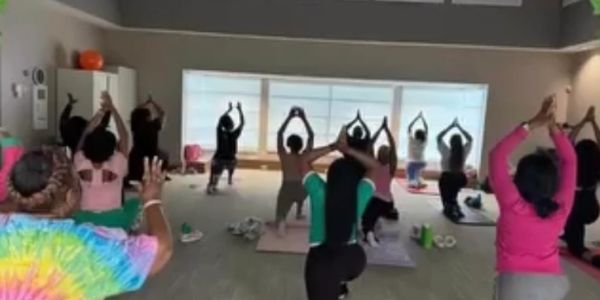 Group yoga session with participants stretching indoors on mats.