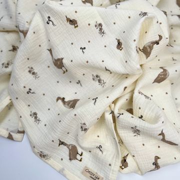 Soft cream-colored fabric with animal and plant prints, ideal for baby blankets.