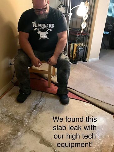 A plumber looking down at the floor inside at a slab leak he found with his high tech equipment