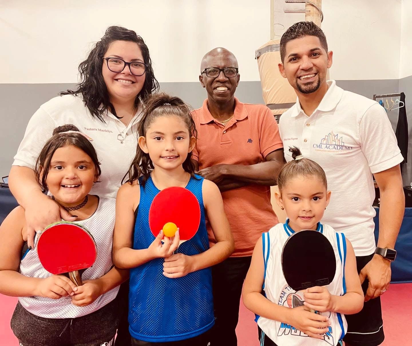 Group photo of people holding ping pong paddles.