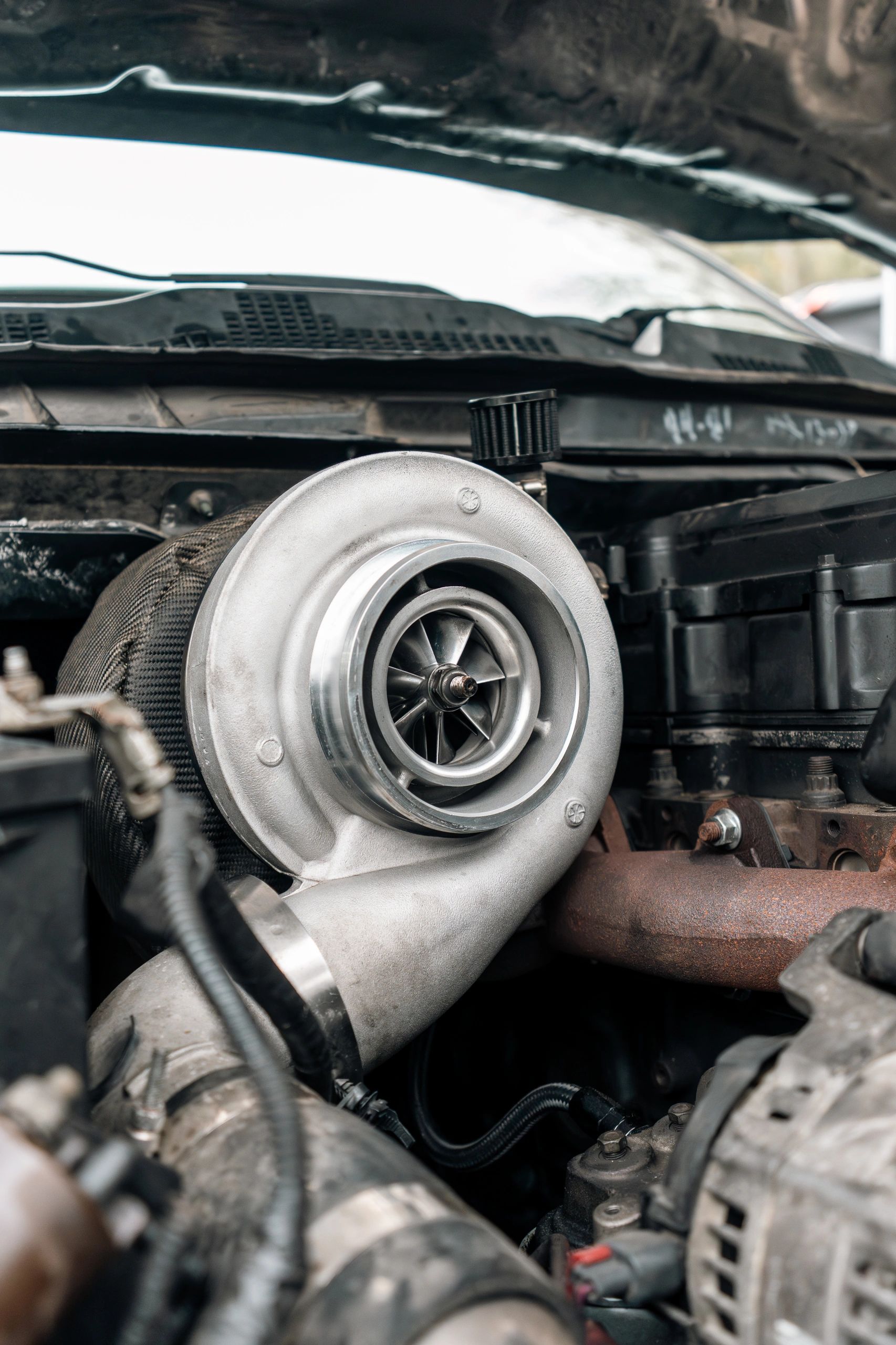 Close-up of a turbocharger installed in a car engine bay.