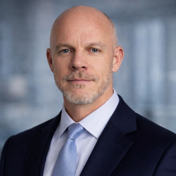 Confident bald man in a suit and tie with a serious expression.
