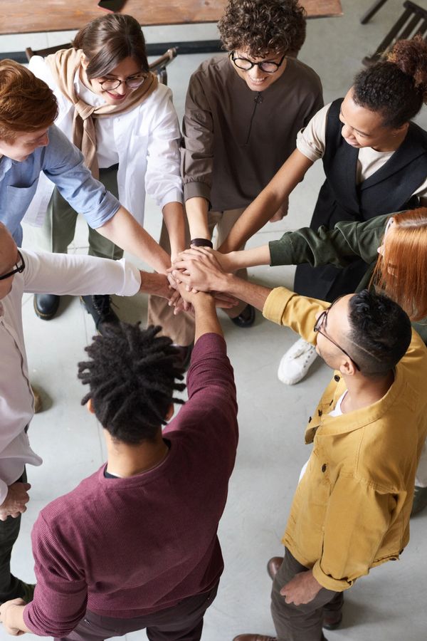 People in a circle gather hands in the middle 