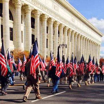 veterans marching the streets as part of a parade holding american flags