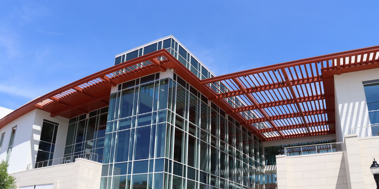 Modern glass building with red architectural accents and outdoor stairs.