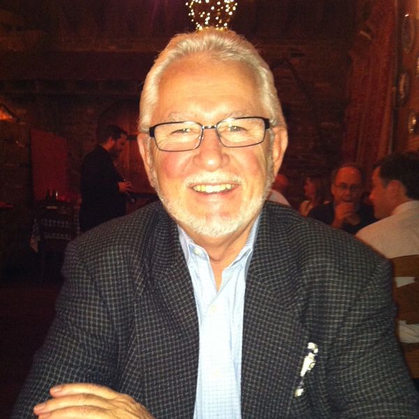 Smiling elderly man with glasses at a cozy restaurant.